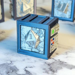 May include: A blue and black cube-shaped game piece with a silver number one die face. The cube has a textured, light-colored background and a series of small, colorful buttons on the side. Other similar cubes are in the background.