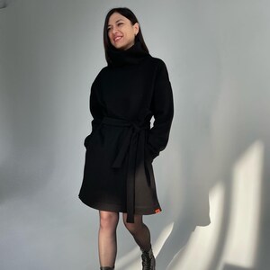 Vestito nero. Caldo abito da donna realizzato in calda felpa di cotone con cintura. Abito in felpa