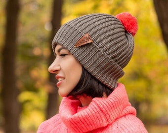 Women's knitted hat made of merino wool. Winter gray knitted hat with four bright pompoms.