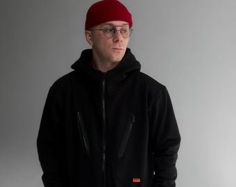 Warme herenjumpsuit met capuchon Morkva Jasper. Zwart winterstuk uit één stuk met zakken en bretels. Gezellige streetwear, outdoorkleding