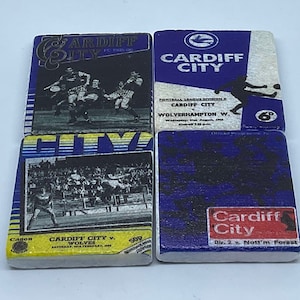 May include: Four vintage-style coasters featuring the Cardiff City Football Club logo. The coasters are made of a white material with a blue and yellow design. The coasters feature images of the team playing and the text "Cardiff City".