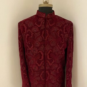 May include: A maroon velvet long-sleeved jacket with a floral pattern. The jacket has a mandarin collar and a front closure.