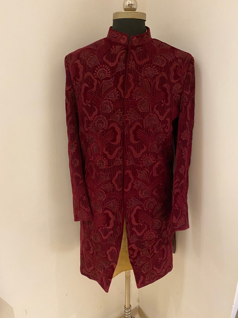 May include: A long, burgundy jacket with a mandarin collar and a floral pattern. The jacket is made of a soft, velvet-like fabric.