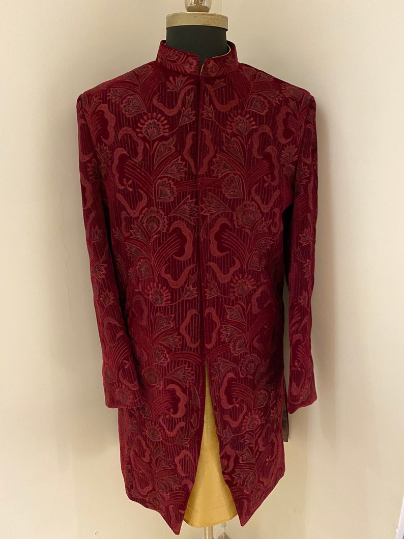 May include: A maroon velvet kurta with a floral pattern. The kurta has a mandarin collar and a long, flowing design.