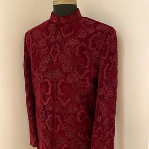 May include: A maroon velvet kurta with a floral pattern. The kurta has a high neck and long sleeves.