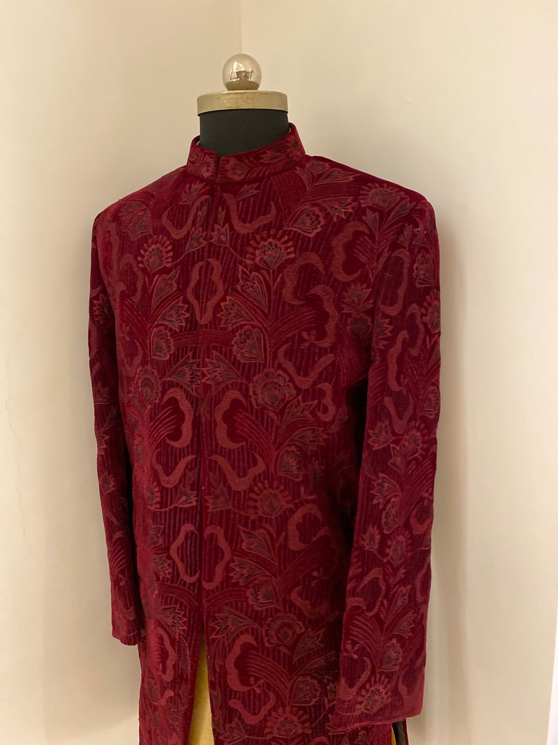 May include: A maroon velvet kurta with a floral pattern. The kurta has a high neck and long sleeves.