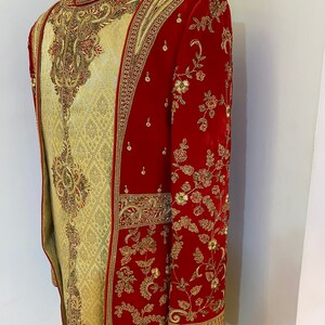 May include: A red and gold embroidered men's garment with a long, flowing design. The garment is made of a velvet fabric and features intricate floral patterns.