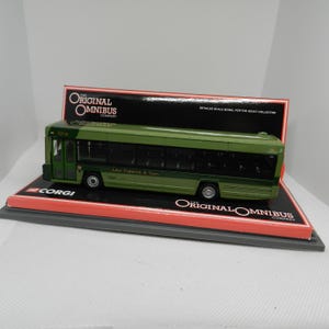Peut inclure: Un modèle de bus vert et blanc avec le texte "The Original Omnibus Company" et "John Fishwick & Sons" sur le côté. Le bus est sur une boîte rouge et grise avec le logo Corgi.