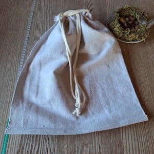 Könnte beinhalten: Eine einfache weiße Kordeltasche aus Stoff mit einem weißen Baumwollkordelzug.