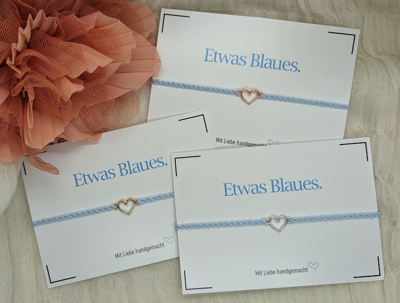 May include: Three blue bracelets with a small heart charm on each. The bracelets are displayed on white cards with the text "Etwas Blaues." and "Mit Liebe handgemacht".