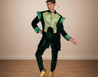 May include: A dark green velvet costume featuring a long-sleeved tunic with a light green textured chest panel, matching trousers, a pointed hat with a small bell, and metallic gold curled-toe shoes. The outfit includes shoulder accents.