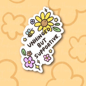 Peut inclure: Un autocollant blanc avec un tournesol jaune, une abeille et des feuilles vertes. Le texte sur l'autocollant est "Unhinged but supportive."
