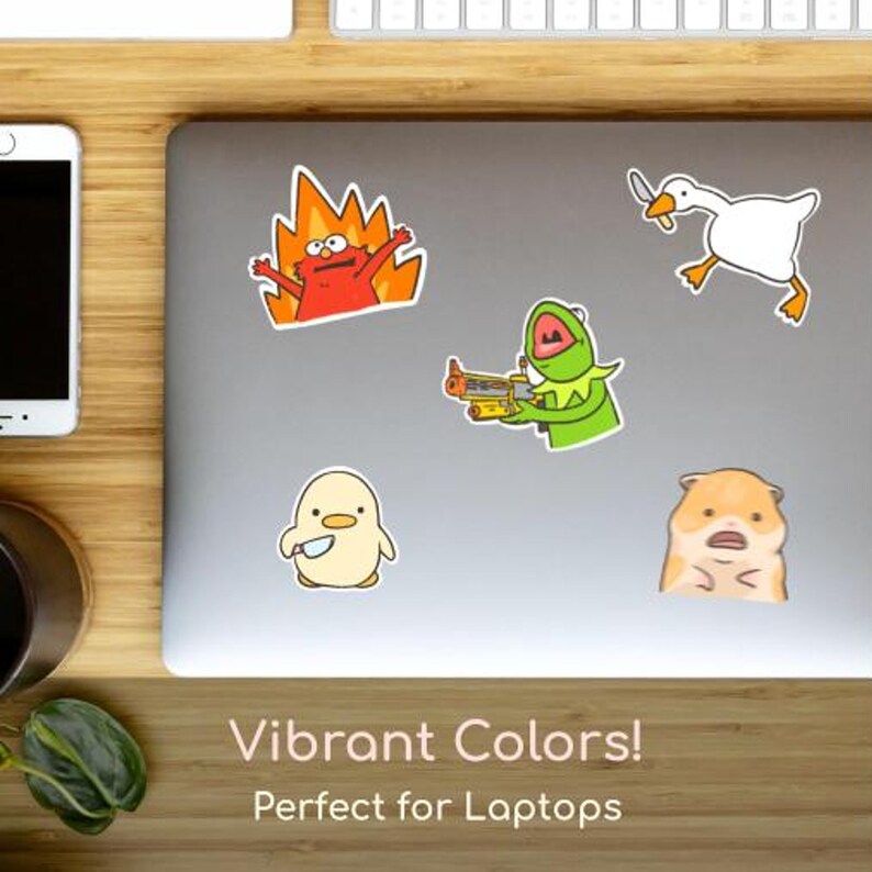 May include: A collection of colorful cartoon stickers on a laptop. The stickers feature various characters, including a red figure engulfed in flames, a green frog holding a blaster, a white goose, a yellow chick with a knife, and a surprised hamster. The text "Vibrant Colors!" is visible.