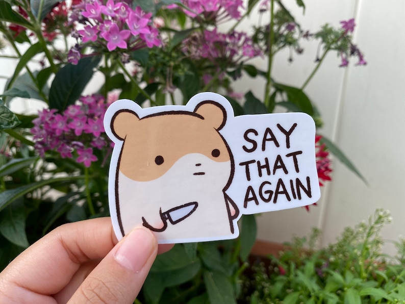 May include: A white sticker with a cartoon hamster holding a knife and the text "SAY THAT AGAIN".