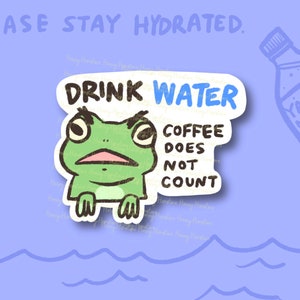 May include: A green frog cartoon sticker with the text "Drink Water" and "Coffee Does Not Count". The sticker is on a light blue background with a cartoon water bottle in the background.