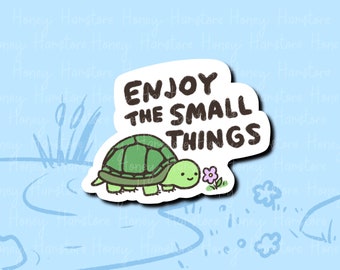 May include: A sticker featuring a cartoon turtle with a green shell and a smiling face, next to a small purple flower. The sticker has the text "ENJOY THE SMALL THINGS" in black letters on a white background.