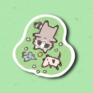 May include: A sticker featuring a cartoon raccoon, opossum, and mouse lying on their backs on a green grassy patch with white flowers.