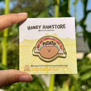 May include: A clear acrylic pin featuring a cartoon potato with a smiling face, set against a rainbow and the words "BE AS LIMITLESS AS A POTATO." The pin is on a yellow card with the Honey Hamstore logo and Etsy shop URL.