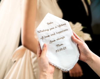May include: White embroidered handkerchief with the text "Bella. Wishing you a lifetime of love and happiness. Love always. Mom. 03.09.25"