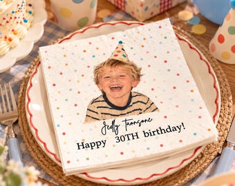 Könnte beinhalten: Eine quadratische weiße Papierserviette mit buntem Punktemuster, einem Foto eines lächelnden Kindes mit Partyhut und dem aufgedruckten Text "Jedly Taonsone Happy 30TH birthday!" in schwarzer Schreib- und serifenloser Schrift.