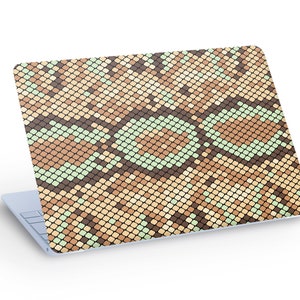 Könnte beinhalten: Ein Laptop mit einem braunen, beige und grünen Schlangenhautmuster auf dem Deckel.