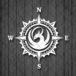 Op de afbeelding: Een zwart-witte kompas met een gestileerd phoenix-ontwerp in het midden. Het kompas wijst naar het noorden, zuiden, oosten en westen.