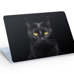 May include: Laptop skin featuring a black cat with bright yellow eyes against a black background. The cat's fur is sleek and glossy, and its whiskers are visible. The laptop is light blue.
