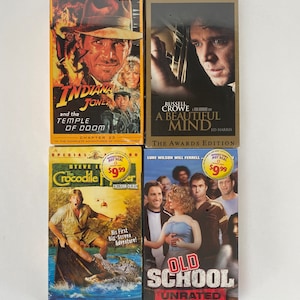 May include: Four VHS tapes of films. The top left tape is Indiana Jones and the Temple of Doom. The top right tape is A Beautiful Mind. The bottom left tape is The Crocodile Hunter: Collision Course. The bottom right tape is Old School.