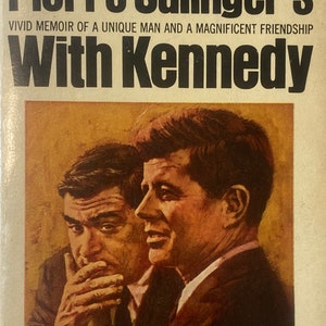 May include: A vintage paperback book cover featuring a black and white photo of Pierre Salinger and John F. Kennedy. The title of the book is "Pierre Salinger's With Kennedy" and the subtitle is "VIVID MEMOIR OF A UNIQUE MAN AND A MAGNIFICENT FRIENDSHIP". The cover also includes the text "The Great Month-After-Month Bestseller" and "With a Selection of Memorable Photographs".