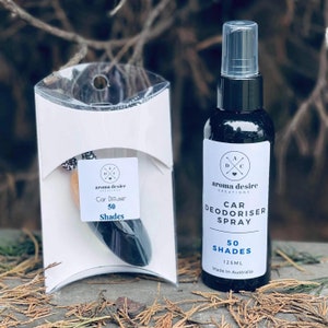 May include: A car air freshener set. It includes a black spray bottle with a white label reading "Car Deodoriser Spray" and "50 Shades", and a car diffuser in a clear package. The spray bottle contains 125ml.