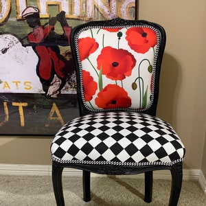 May include: Black and white checkered chair with a black frame and a red poppy floral patterned seat back.