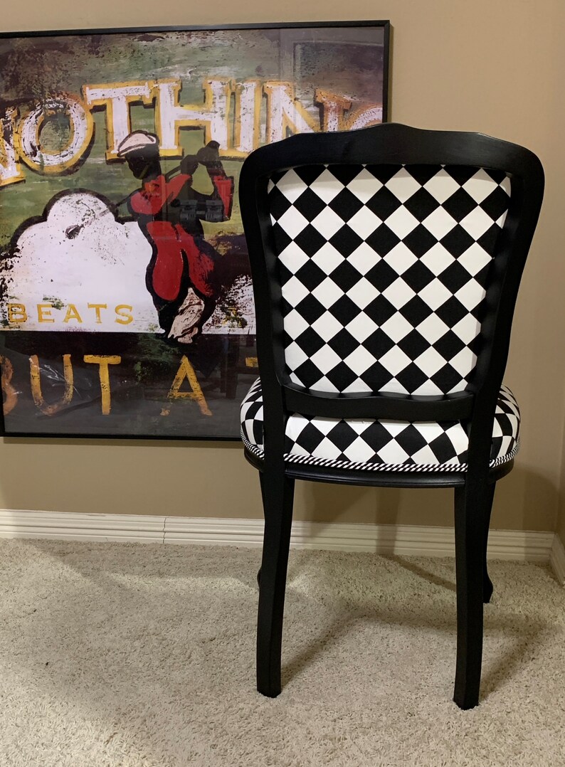 May include: Black and white checkered dining chair with a black wooden frame. The chair has a curved back and a padded seat.