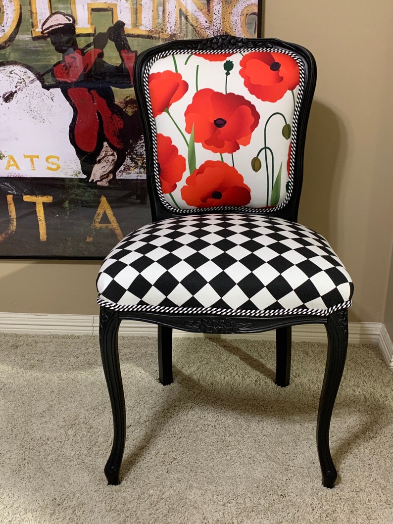 May include: Black and white checkered chair with a black frame and a red poppy floral patterned seat back.