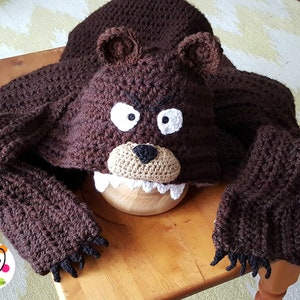 May include: Brown crocheted bear hooded blanket with black claws and a white and brown bear face.