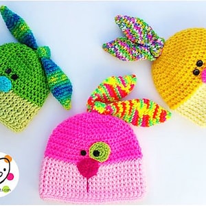 May include: Three crocheted bunny hats in pink, green, and yellow with colorful yarn accents. The hats have embroidered eyes and noses.