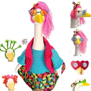 Könnte beinhalten: Eine weiße Gänsefigur, die eine Vielzahl von bunten Häkelmützen, Perücken und Sonnenbrillen trägt. Die Gans ist mit einem blauen und rosa Häkelpullover und einem bunten Häkelrock bekleidet.