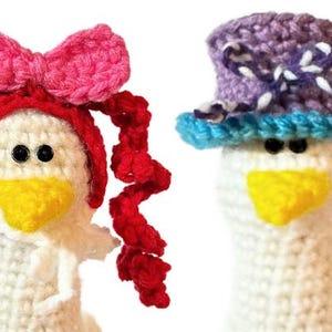 May include: Four white crochet goose figures, each adorned with a different hat and accessories. The hats include a black top hat, a pink bow, a purple top hat, and a blue hat with orange hair. Each goose has a yellow beak and black eyes.