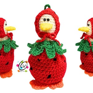 May include: Crocheted duck figurine dressed as a strawberry. The duck wears a red strawberry costume with green leaves and a matching hood. The duck has a yellow beak and orange feet. The figurine is handmade and suitable for home decor.