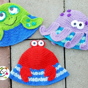 May include: Three crocheted hats shaped like a turtle, octopus, and crab. The turtle hat is green with blue accents, the octopus hat is purple with blue accents, and the crab hat is red with blue and white accents.