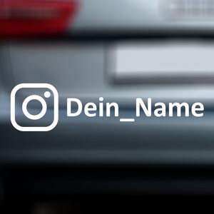 Könnte beinhalten: Ein weißes Instagram-Logo mit dem Text "Dein_Name" auf einem grauen Auto.