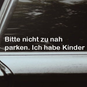 Könnte beinhalten: Ein schwarzes Auto mit einem Schild, auf dem "Bitte nicht zu nah parken. Ich habe Kinder." in weißer Schrift steht.