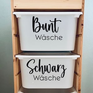Könnte beinhalten: Drei weiße Plastik-Aufbewahrungsbehälter mit Holzetiketten. Der obere Behälter trägt die Aufschrift "Bunt Wäsche", der mittlere Behälter die Aufschrift "Schwarz Wäsche" und der untere Behälter die Aufschrift "Koch Wäsche".