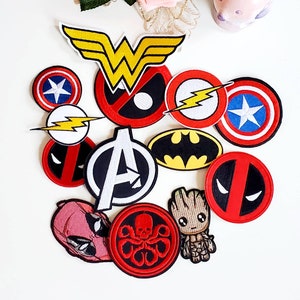 Puede incluir: Una colecci&oacute;n de parches bordados coloridos con logotipos y personajes de superh&eacute;roes. Incluye el logotipo de Wonder Woman, el escudo del Capit&aacute;n Am&eacute;rica, el emblema de Batman y la m&aacute;scara de Deadpool. Otros parches incluyen Flash, el logotipo de los Vengadores, Groot y una calavera roja.