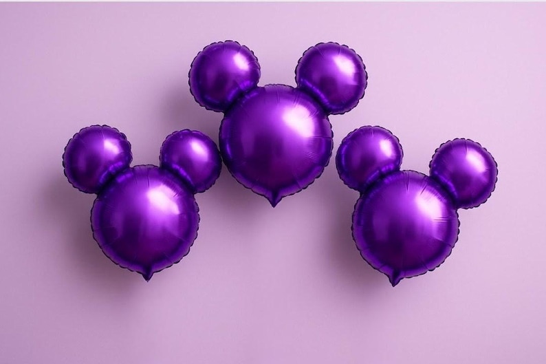 Puede incluir: Tres globos de papel de aluminio morados con forma de Mickey Mouse sobre un fondo lila claro. Los globos tienen un acabado brillante y met&aacute;lico y est&aacute;n dispuestos en fila. Perfecto para una fiesta de cumplea&ntilde;os o evento tem&aacute;tico.