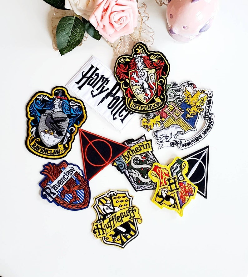 Puede incluir: Un conjunto de parches bordados con dise&ntilde;os de la serie Harry Potter. Los parches incluyen los escudos de las casas de Hogwarts: Gryffindor, Ravenclaw, Hufflepuff y Slytherin, junto con un parche que dice "Harry Potter" y el s&iacute;mbolo de las Reliquias de la Muerte.