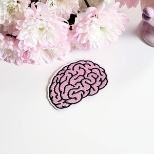 May include: Pink embroidered brain patch with black outline. The patch is on a white background.