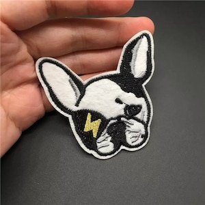 May include: Black and white embroidered iron-on patch of a French bulldog with a lightning bolt design.