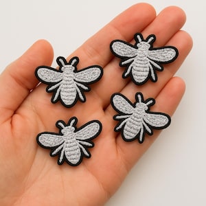 Set med 4 silverfärgade broderade strykmärken med bin och flugor