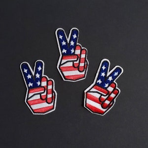 May include: Three peace sign patches with the American flag design. The patches are red, white, and blue with white stars on a blue background.