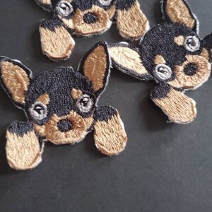 May include: Three embroidered iron-on patches of black and brown chihuahua dogs with white eyes.